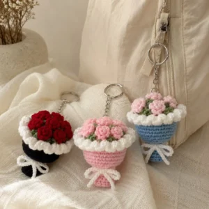Red, pink and blue handmade crochet bouquet keychains beside a cream bag